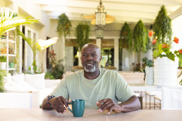Portrait of happy senior african american man with cup of coffee having video call
