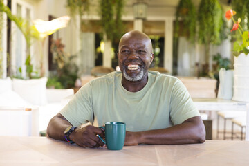 Portrait of happy senior african american man with cup of coffee having video call