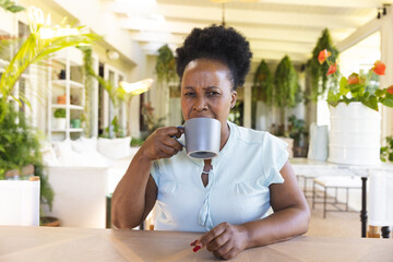 Portrait of shocked senior african american woman with cup of coffee having video call