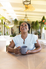 Happy senior african american woman with cup of coffee having video call