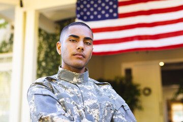 Portrait of biracial male american soldier wearing military uniform standing outside the house