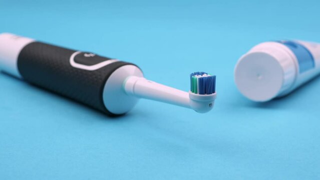 brosse &agrave; dents &eacute;lectrique avec un tube de dentifrice ferm&eacute; sur un fond bleu uni