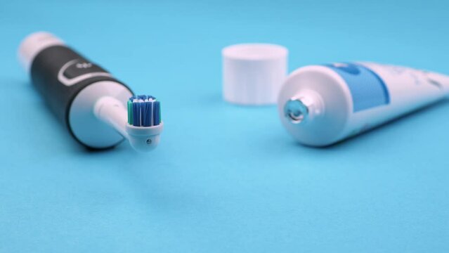 brosse &agrave; dents &eacute;lectrique avec un tube de dentifrice neuf sur un fond bleu uni
