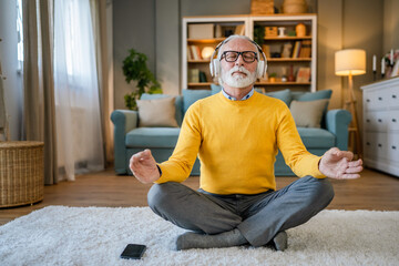 Fototapeta premium Mature senior man practice guided meditation manifestation at home