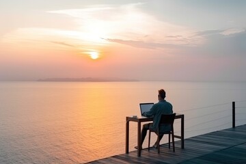 Fototapeta na wymiar Man working remotely with his laptop from luxury location with the beautiful view on the sunset. He is enjoying the view on the sea. Created with generative AI