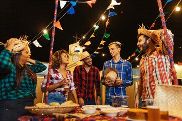 Festa Junina. Group of friends gathered at the typical food table.