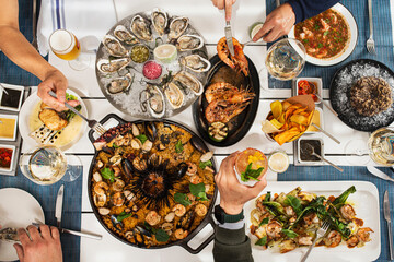 plano cenital de varios platos de mariscos y copas de vino sobre manteles azules 