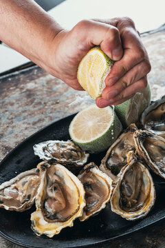 ostras frescas al natural con limon exprimido servidas en un plato negro