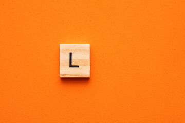 Alphabet letter L on wooden square tile - Orange foamy background