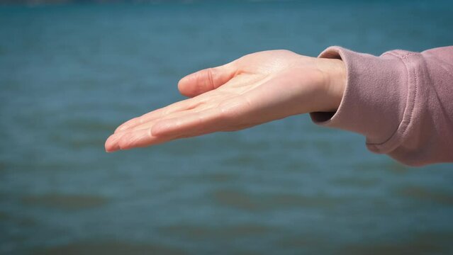 Give money by sea. A girl give money to a beggar on the sunny shore.