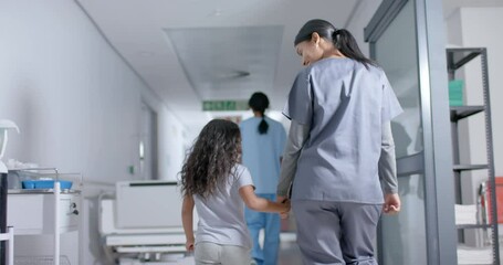 Diverse female nurse and child patient walking through corridor at hospital, in slow motion - Powered by Adobe