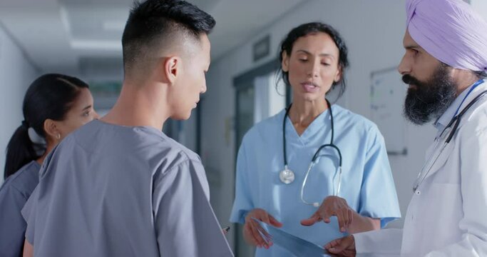 Diverse doctors and nurses talking in corridor at hospital, in slow motion