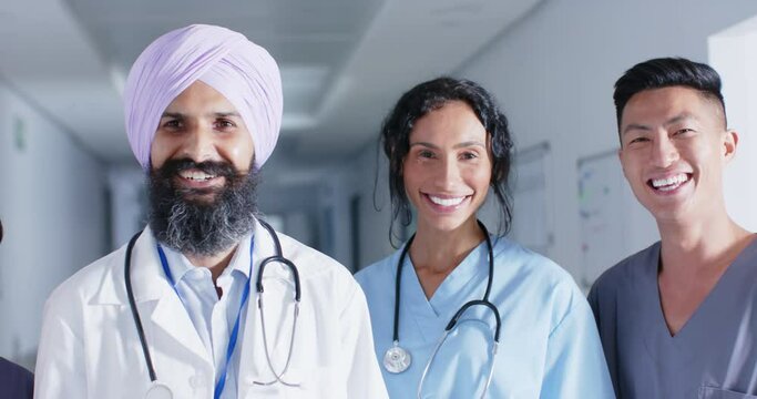 Portrait of diverse doctors and nurses smiling in corridor at hospital, in slow motion