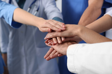 Obraz premium Team of medical doctors putting hands together indoors, closeup