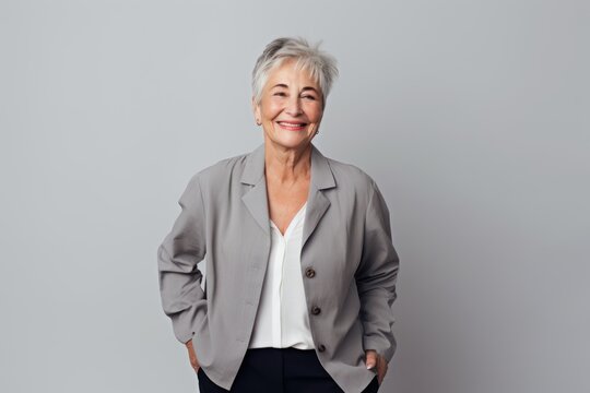 portrait of smiling senior businesswoman looking at camera isolated on grey