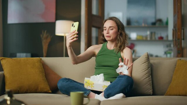 Unhappy girl speaking phone holding napkin. Sad woman trying calm online therapy