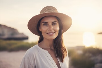 Portrait of beautiful young woman in hat on the beach at sunset