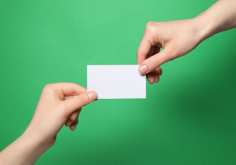 Women holding blank gift card on green background, closeup