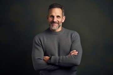 Portrait of a handsome mature man in a gray sweater on a dark background