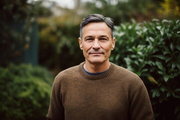 Portrait of handsome middle-aged man in brown sweater standing outdoors