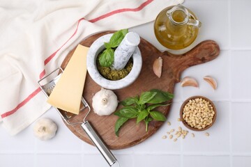 Different ingredients for cooking tasty pesto sauce on white tiled table, flat lay