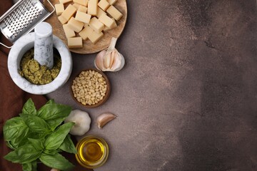 Tasty pesto sauce and ingredients on brown textured table, flat lay. Space for text