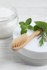 Toothbrush, dental products and herbs on white wooden table, closeup