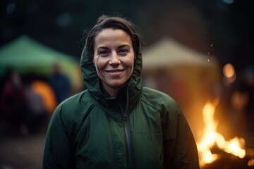 Portrait of a woman in a green raincoat standing at the campfire