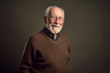 Obraz premium Portrait of a senior man in a brown sweater on a gray background