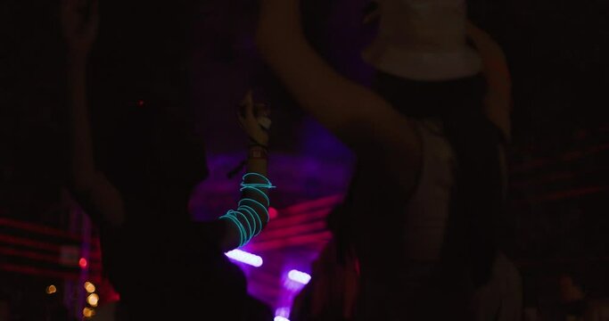 Two young girls dancing in crowd in front of stage. Low light video.