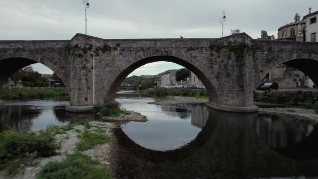 Drone flies under a bridge to reveal beautiful river and village in France