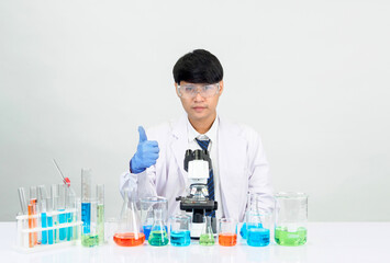 Asian male student scientist in reagent mixing laboratory In a science research laboratory with test tubes of various sizes and microscopes. on the table in  laboratory chemistry lab white background.