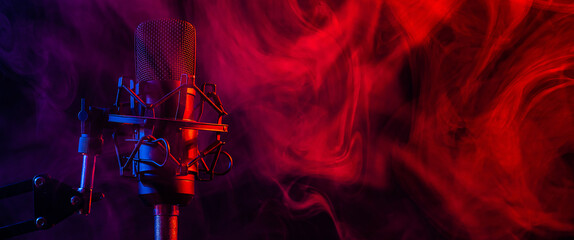 Professional microphone in red blue smoke on a black background. Widescreen. 
