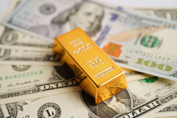 Gold bars on US dollar banknote money, finance trading investment business currency concept.