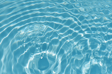 Blue water with ripples on the surface. Defocus blurred transparent blue colored clear calm water surface texture with splashes and bubbles. Water waves with shining pattern texture background texture