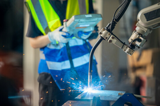 Engineer control robot arm machine welding steel, worker using forcing welding control screen which for precision welding control. Worker control automation welding robot in hi tech heavy factory
