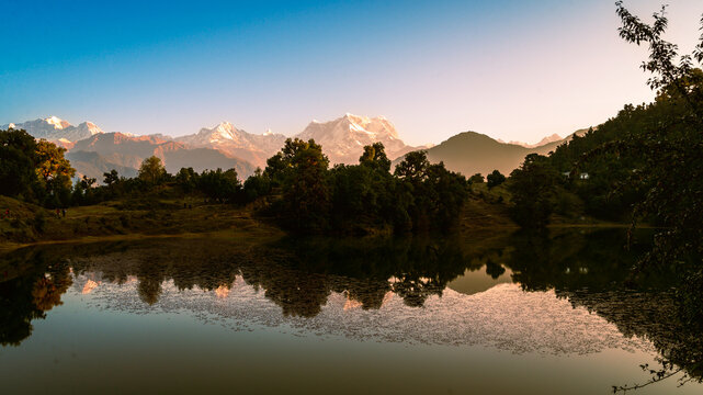 Sunrise over the lake. Serene view of the reflection of trees in lake called Deoria Tal.  Lake nestled in  Himalayas at Garhwal region.  Chopta, Tungnath, Chandrashila hiking trail, Uttarakhand, India