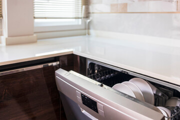 Dishwasher inside beautiful kitchen with white used dishes that prepared to wash.Electronic dish...