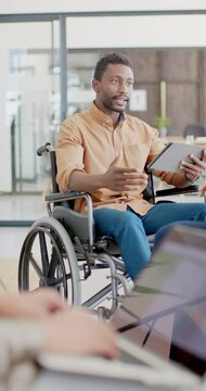 Vertical video of disabled african american in wheelchair with tablet talking in slow motion