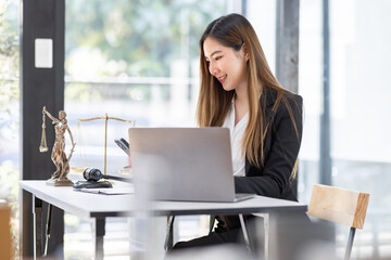 Obraz premium Lawyer business Asian woman office. Statue of Justice with scales and lawyer working on a laptop workplace . Legal law, advice and justice concept.