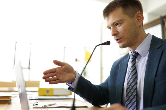 Focused manager speaks in microphone at online seminar