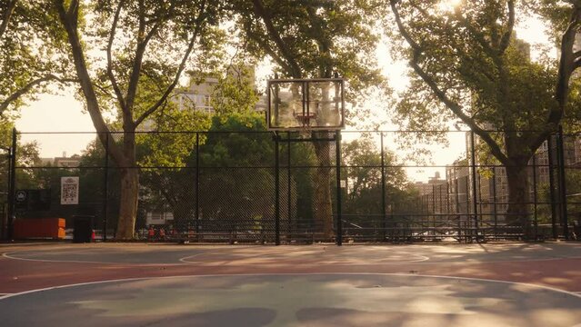 Backwards shot on empty basketball court in New York city near central park at sunset
