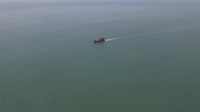 Aerial shot of fishing boat in the middle of the sea fishing.