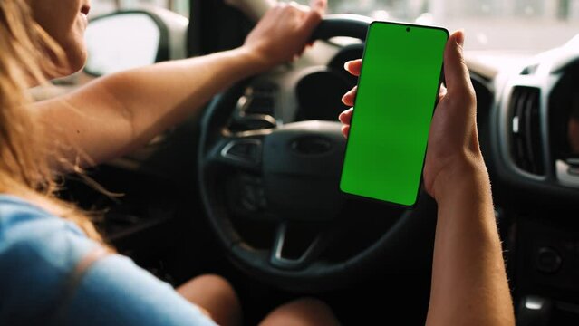 Female driver using a smartphone inside the car. Chromakey smartphone with green