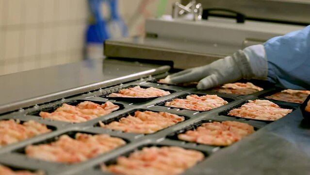 Gloves worker placed black trays of shrimp or shellfish onto holder in conveyor belt