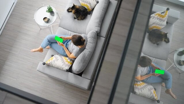 Overhead shot of woman using smartphone with green mock-up screen