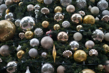 Large gold and silver ornaments on a Christmas tree.