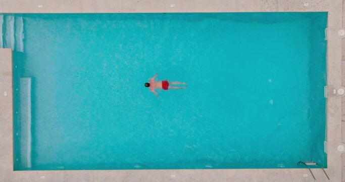 Aerial view as a man dives into the pool and swims.