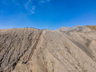 The caldera and the peak of Mount Bromo are photographed from a height. It looks like the tourists are climbing and enjoying the peak. Mt.Bromo is a popular tourist destination in East Java, Indonesia