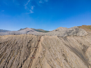 The caldera and the peak of Mount Bromo are photographed from a height. It looks like the tourists are climbing and enjoying the peak. Mt.Bromo is a popular tourist destination in East Java, Indonesia